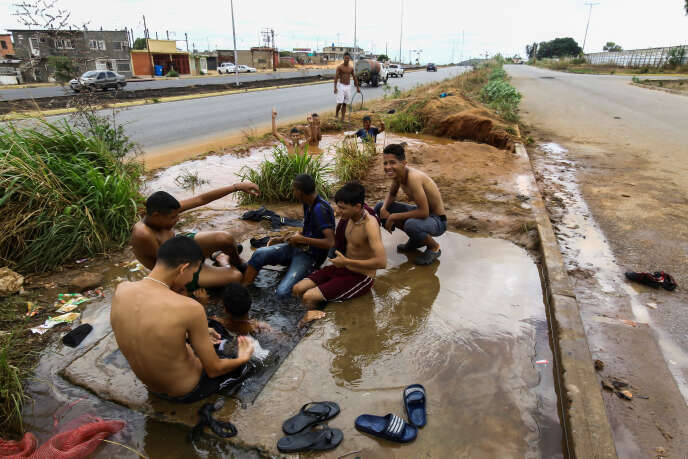 Des gens se lavent dans la rue grâce à une canalisation percée, à San Felix, le 12 mars.