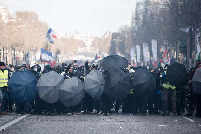 Des manifestants avancent abrités par des parapluies, le 16 mars à Paris.