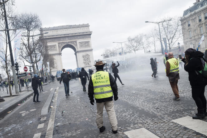 Avenue des Champs-Elysées, à Paris, le 16 mars, lors de l’acte XVIII des « gilets jaunes ». Un manifestant porte sur son gilet l’inscription « on lâche rien !… aaouuu !