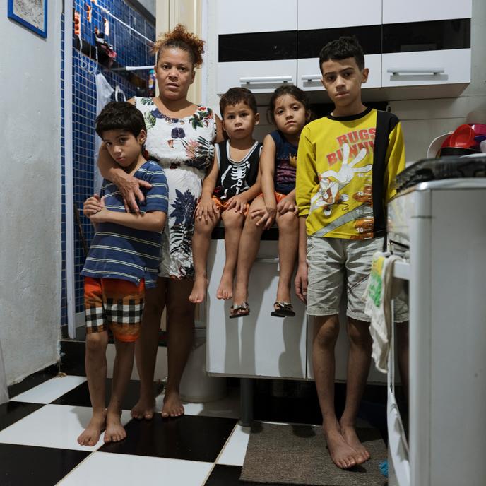 Maria de Ajuda, left his son Peter Texeira, and from right to left his godson Antonio Vince, Cristal Texeira (his daughter) and Marcos Gonçalves (his eldest son) in the kitchen of their apartment, occupation 9 de Julho, Bela Vista neighborhood in Sao Paulo - Brazil. The husband of Maria, Franck is absent this day, he lost his job of porter of building in the center of Sao Paulo 2 months ago.