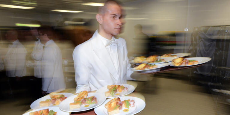 Des serveurs receptionnent les plats à servir à l'occasion d'une réception d'un grand restaurant