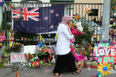 A mourner carries a bouquet as tributes for victims of the Christchurch twin mosque massacre are seen in front of the Jamia Masjid mosque in Hamilton on March 22, 2019. - The Muslim call to prayer rang out across New Zealand on March 22 followed by two minutes of silence nationwide to mark a week since a white supremacist gunned down 50 people at two mosques in the city of Christchurch. (Photo by MICHAEL BRADLEY / AFP)