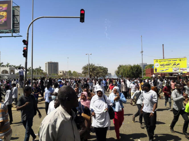 Des manifestants tentent d’éviter le gaz lacrymogène utilisé par les forces de l’ordre près du quartier général de l’armée, à Khartoum, le dimanche 7 avril.