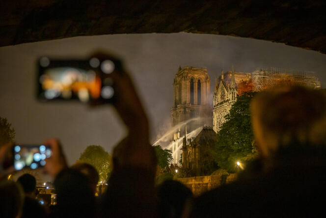 Les yeux et les caméras des passants sont tournés vers la cathédrale qui se consume, sur les quais de Seine, à Paris, le 15 avril.