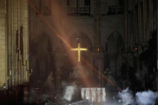La fumée enveloppe l’autel où trône la croix, à l’intérieur de Notre-Dame de Paris, après l’incendie qui a ravagé la cathédrale, mardi 15 avril 2019.