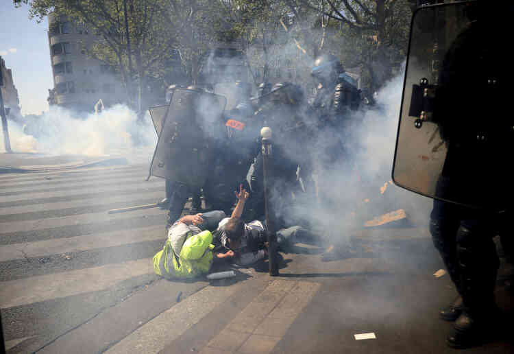 Des membres des forces de l’ordre chargent des manifestants, à Paris, le 20 avril.