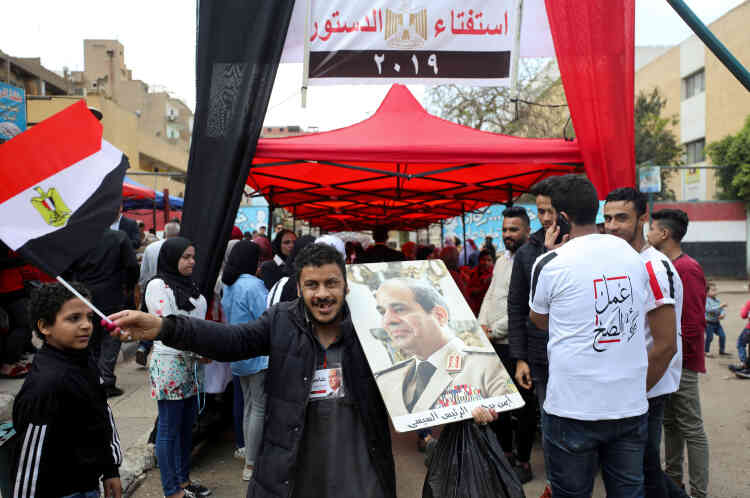 A la sortie d’un bureau de vote, un homme brandit un drapeau national et un portrait de M. Sissi, le président égyptien, le 20 avril, au Caire.