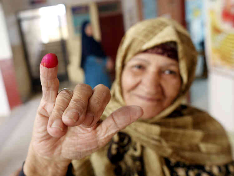Une Egyptienne montre son doigt recouvert d’encre rose après avoir voté, le 21 avril, au Caire. Avec la preuve de leur vote, certains élécteurs peuvent ensuite récupérer un colis de nourriture dans un magasin avoisinant, dans lequel ils trouvent du sucre, de l’huile, du riz, des macaronis et de la sauce tomate.