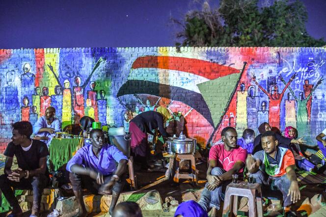 Des manifestants soudanais devant une peinture murale réalisée près du QG de l’armée à Khartoum, le 24 avril.