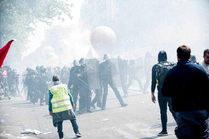 A la manifestation du 1er-Mai, à Paris, « gilets jaunes », syndicats et CRS, au milieu d’un nuage de gaz lacrymogènes.
