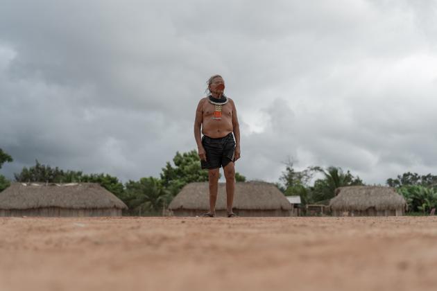 Dans son village de Metuktire, Raoni s’adresse aux villageois devant les huttes traditionnelles en rondins de bois et feuilles de palmier.