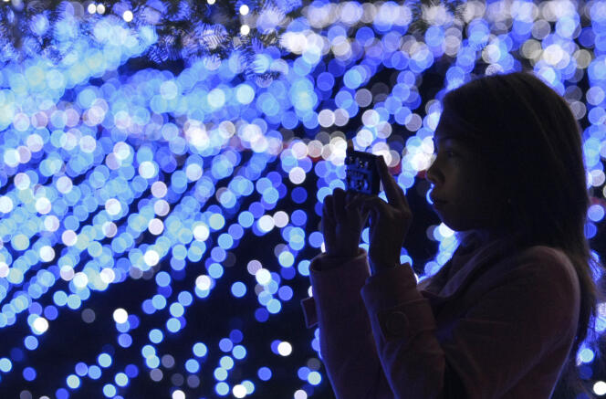 Une femme prend en photo une installation de LED bleues à Tokyo en 2009.