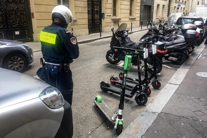 Un agent de surveillance de Paris déplace des trottinettes mal garées, le 6 juin à Paris.
