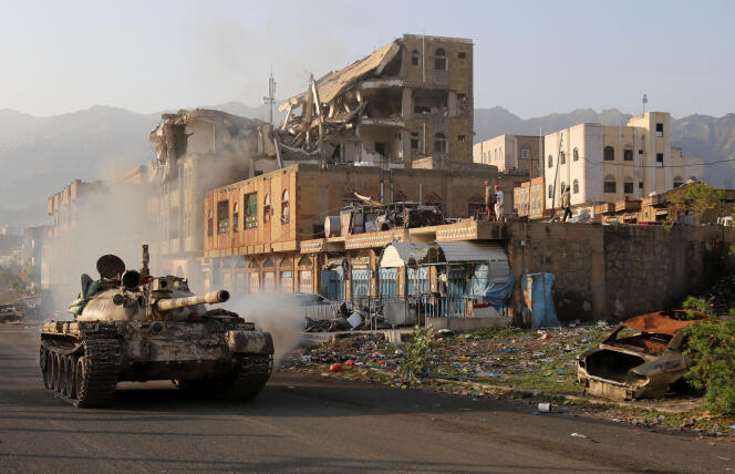Des combattants yéménites, fidèles au président exilé Abd Rabbo Mansour Hadi, circulent à côté d’un bâtiment détruit lors d’un affrontement avec des rebelles chiites, dans la troisième ville du pays, Taez, le 30 mai 2019.