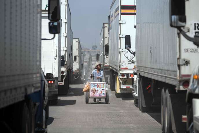 Un vendeur ambulant circule entre les camions de marchandises qui attendent de passer la frontière, à Tijuana (Mexique), le 6 juin.