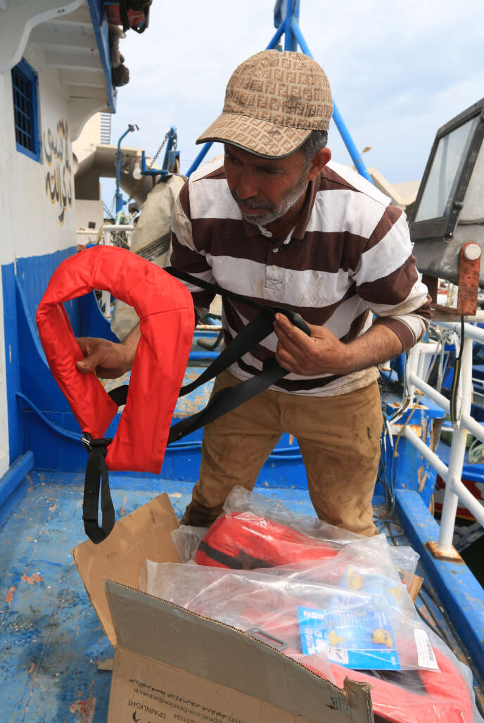 Le 21 mai 2019, dans le port de Zarzis, voisin de la Libye, un capitaine de petit chalutier tunisien prépare des gilets de sauvetage avant de partir faire sa pêche.