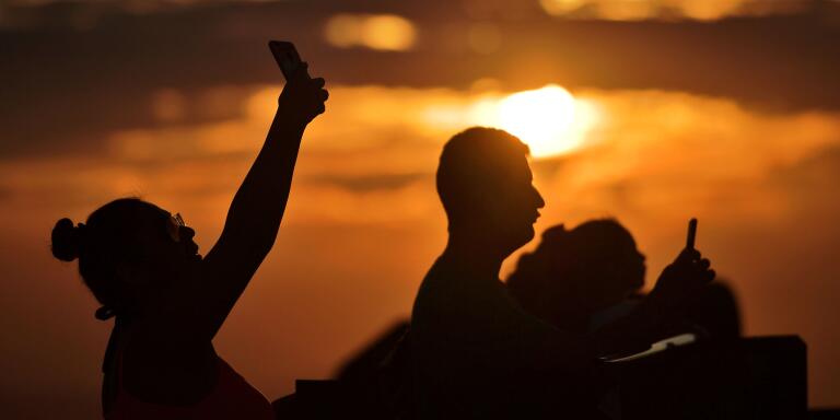 Tourists take selfies by the Christ the Redeemer statue on June 13, 2019.  / AFP / CARL DE SOUZA
