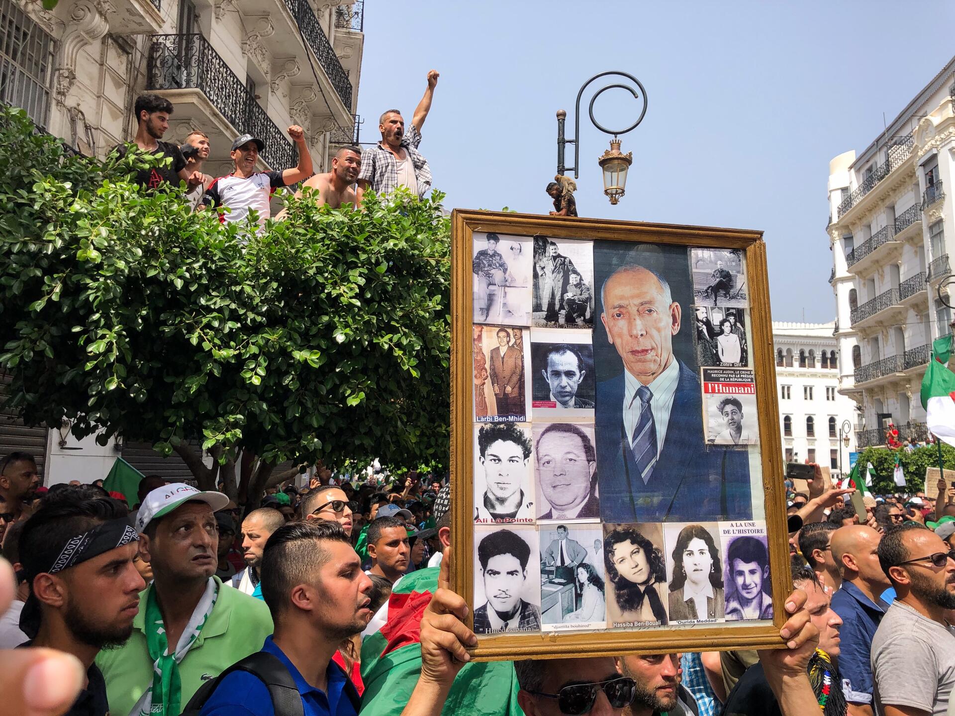 Un manifestant brandit des portraits de figures de la révolution algérienne.