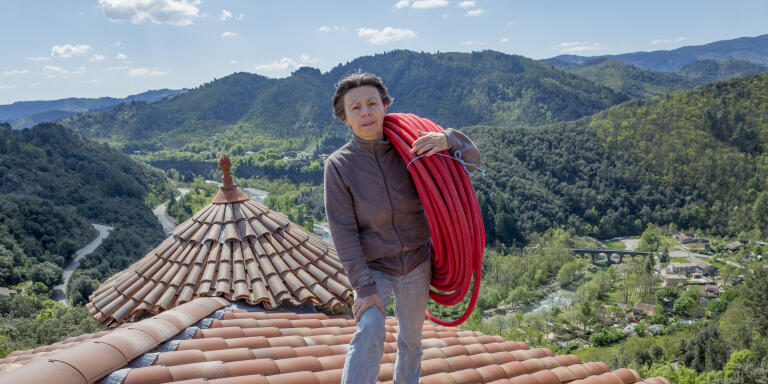 Patricia Demangeon sur le toit de son chateau avec un rouleau de tube PER gainé pour l'alimentation en eau chaude de la pièce en dessous. Chateau de Hautsegur, Meyras, France 30/04/2019.