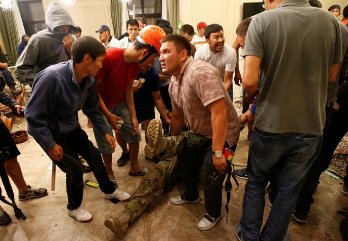 Des partisans armés d’Almazbek Atambaïev entourent un membre blessé des forces spéciales fait prisonnier à l’intérieur de la résidence de l’ancien chef d’Etat, à Koï-Tach le 7 août 2019.