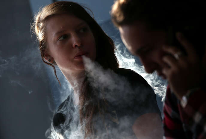 Una joven mujer fuma un cigarrillo electrónico en San Rafael, California.  En 2018, uno de cada cinco estudiantes de secundaria estadounidenses estaba vapeando.