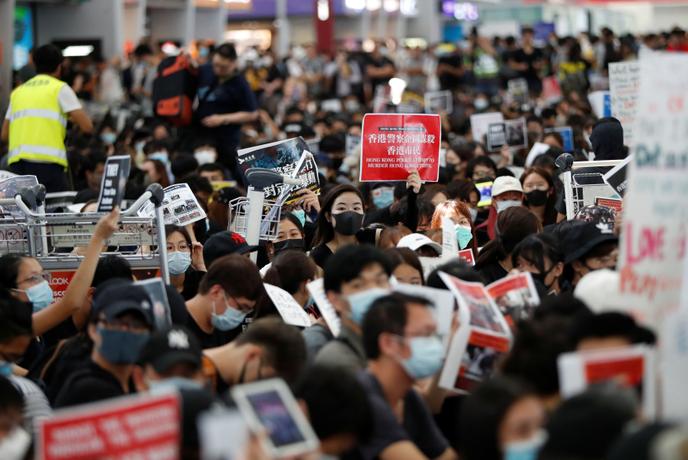 Des manifestants antigouvernementaux sont assis par terre devant les barrières de sécurité lors d’une manifestation à l’aéroport de Hongkong, en Chine, le 13 août 2019.