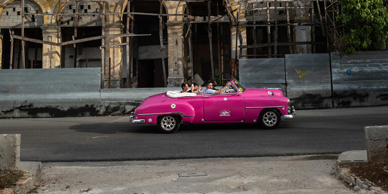 An American old car rolls with tourists in front of an old building in Old Havana, Cuba,  July 8, 2019.