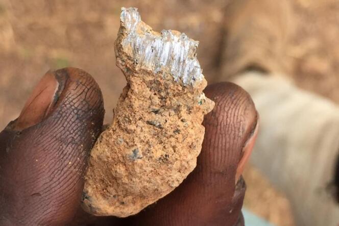 Un homme travaillant à la décharge de déchets miniers de Kabwe montre un morceau de roche, en 2018.