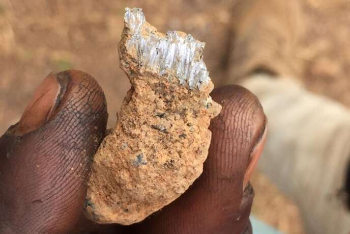 Un homme travaillant à la décharge de déchets miniers de Kabwe montre un morceau de roche, en 2018.