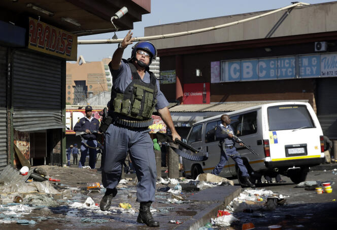 Un officier de police lançant une grenade lacrymogène, mardi 3 septembre à Germiston, un quartier de l’est de Johannesburg (Afrique du Sud).