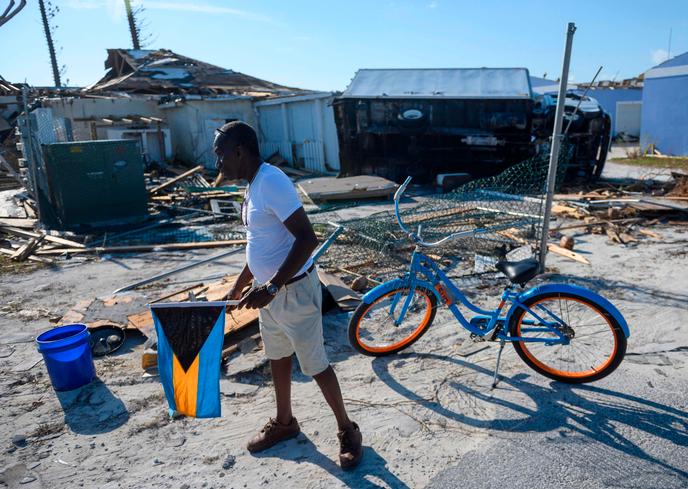 Un habitant des Bahamas marche parmi les décombres, le drapeau national à la main, sur l’île Abaco, le 11 septembre 2019.