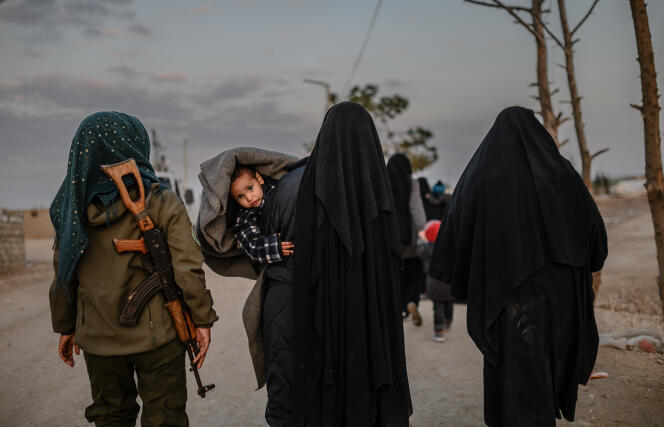 Des femmes voilées escortées par une combattante des Forces démocratiques syriennes, dans le camp d’Al-Hol, le 17 février.