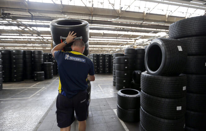 Un ouvrier pousse un chariot avec des pneus de sport automobile, dans l’usine  Michelin à Clermont-Ferrand, le 10 juillet 2013.