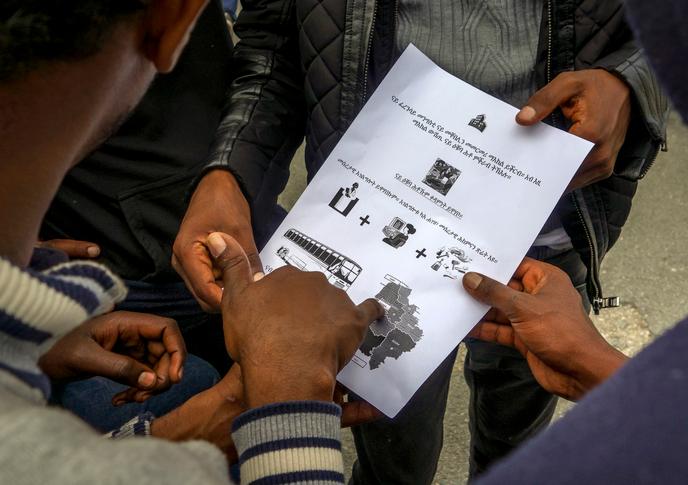 A Calais, en août 2016, des migrants en provenance d’Erythrée, en Afrique de l’Est, lisent le document d’information, formulé en tigréen, sur la procédure de demande d’asile.
