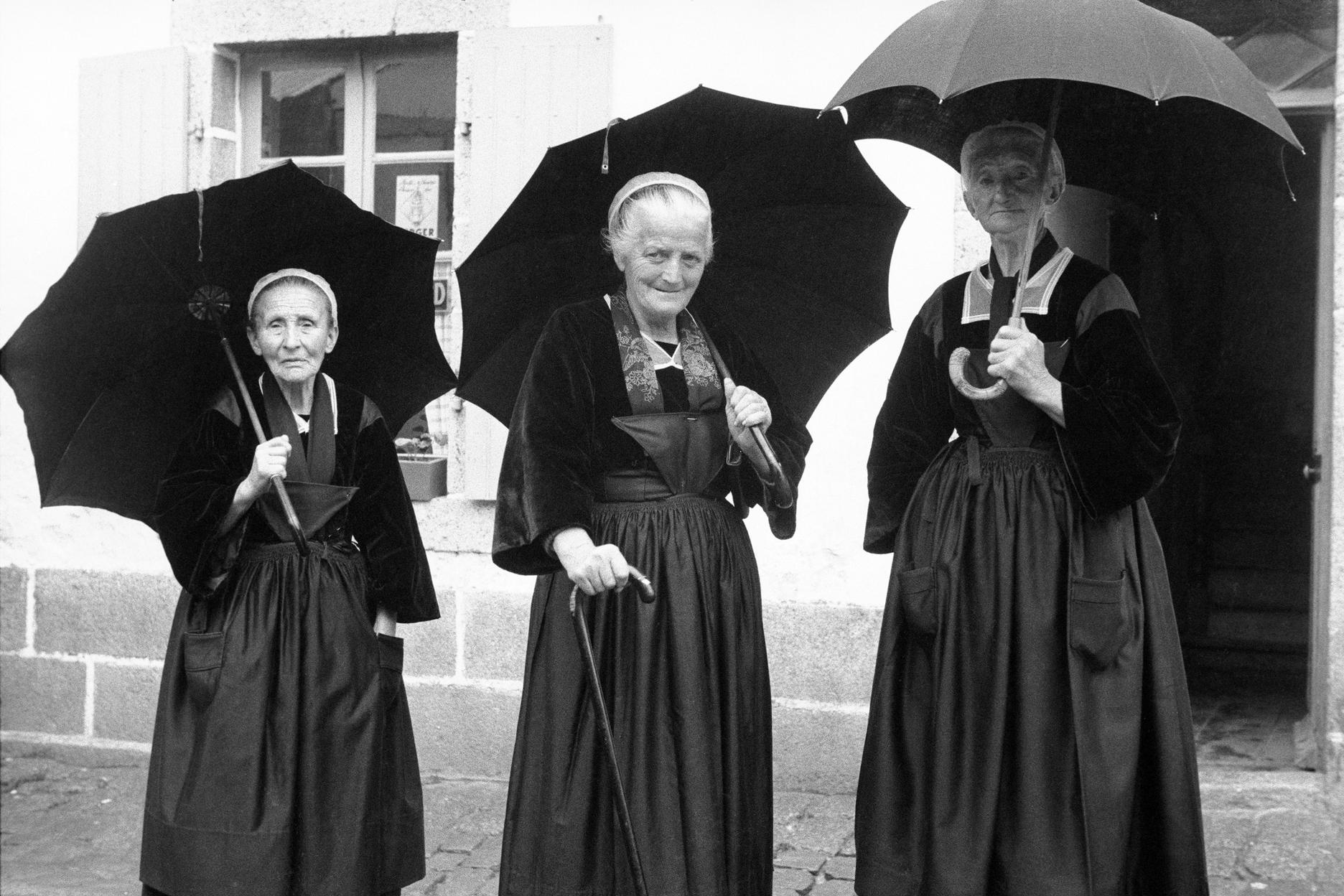« Au détour d’une rue, je croise ces trois Bretonnes qui discutaient. Voyant que je sortais mon appareil, elles m’ont fait face avec amusement et plaisir. Elle ne se doute pas que les parapluies les encadrent si joliment. C’est une photographie que j’affectionne particulièrement et qui dépasse, pour moi, l’anecdote. »