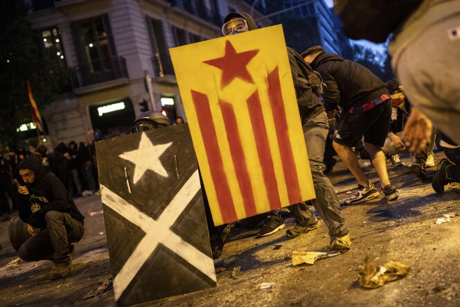 Des manifestants équipés de boucliers avec le drapeau indépendantiste catalan affrontent la police à Barcelone, le 18 octobre.