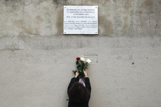 Une femme installe des fleurs en-dessous d’une plaque commémorative, près du Carillon et du Petit Cambodge, à Paris , le 13 novembre 2018.