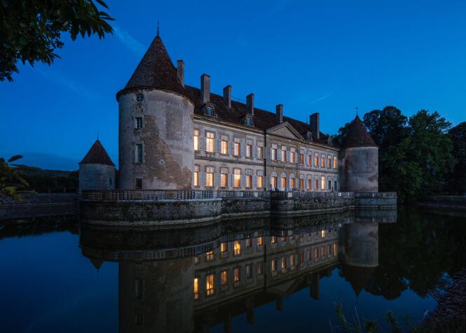 La nuit, le château de Missery se reflète dans l’eau de ses douves.