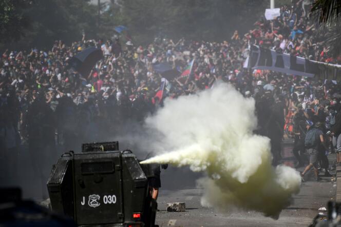 Un véhicule des forces de l’ordre face à des manifestants, à Santiago, mardi 22 octobre 2019.