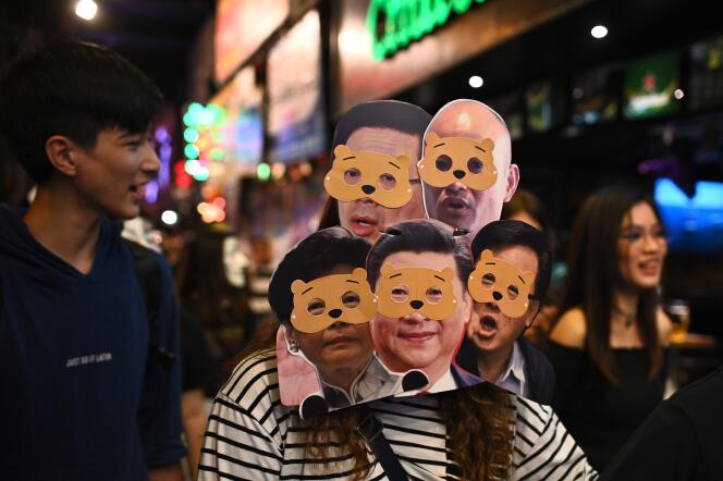 Des manifestants portent des masques de Carrie Lam et de Xi Jinping tournés en dérision.
