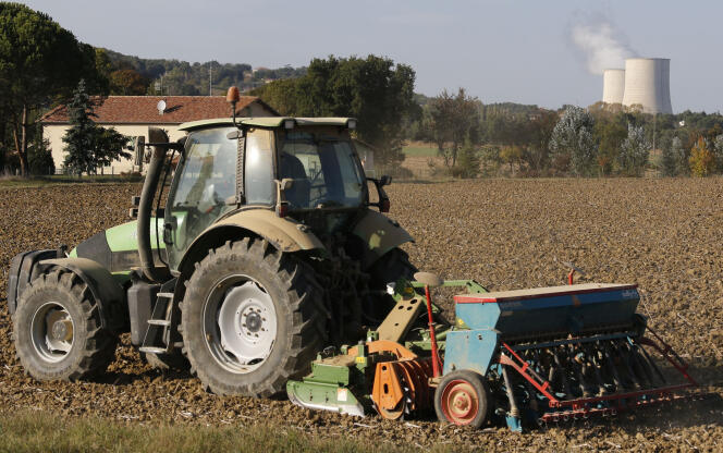 Un agriculteur cultive son champ à proximité des tours de refroidissement de la centrale nucléaire de Golftech (Tarn-et-Garonne), en octobre 2014.
