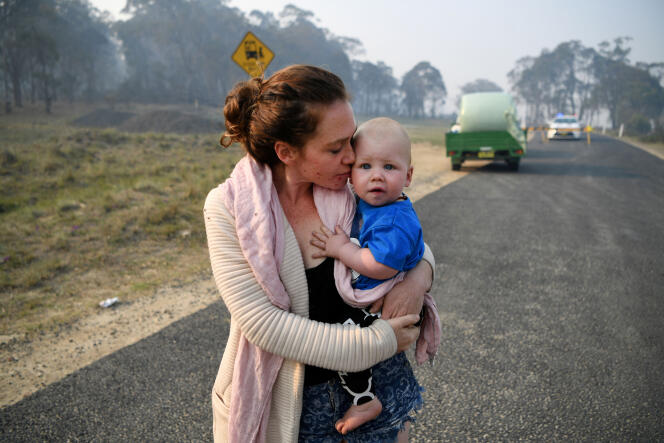 Une habitante de Wytaliba tient son fils dans ses bras alors qu’elle attend de pouvoir rentrer chez elle à un barrage routier près de Glen Innes, Australie, le 11 novembre 2019.