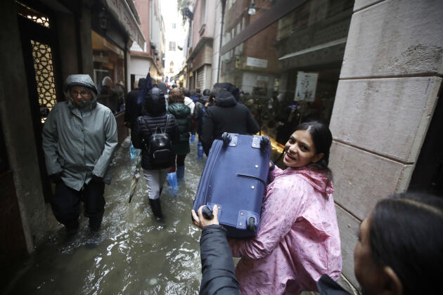Les touristes transportent leurs bagages dans les rues où le niveau de l’eau est monté de façon exceptionnelle, le 12 novembre.