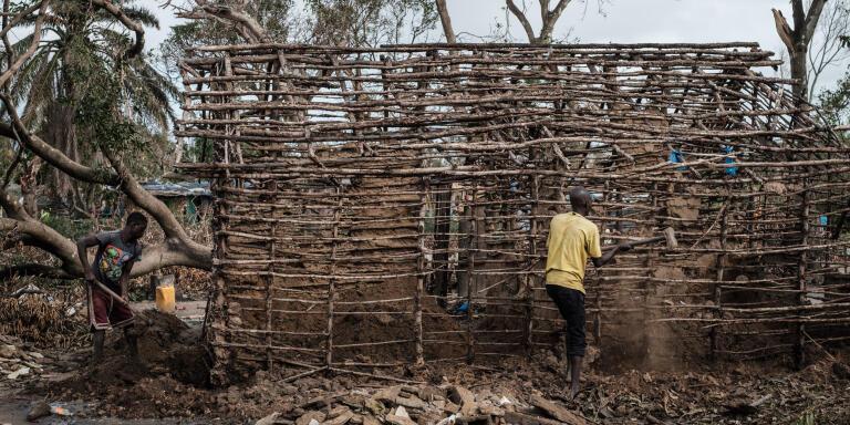 Men remove the remaining of mudwall as they repair their house which was destroyed by the winds of cyclone Idai in Beira, Mozambique, on March 27, 2019. - Five cases of cholera have been confirmed in Mozambique following the cyclone that ravaged the country killing at least 468 people, a government health official said on March 27, 2019. Cyclone Idai smashed into Mozambique on March 15, unleashing hurricane-force winds and heavy rains that flooded much of the centre of the poor southern African country and then battered eastern Zimbabwe and Malawi. (Photo by Yasuyoshi CHIBA / AFP)