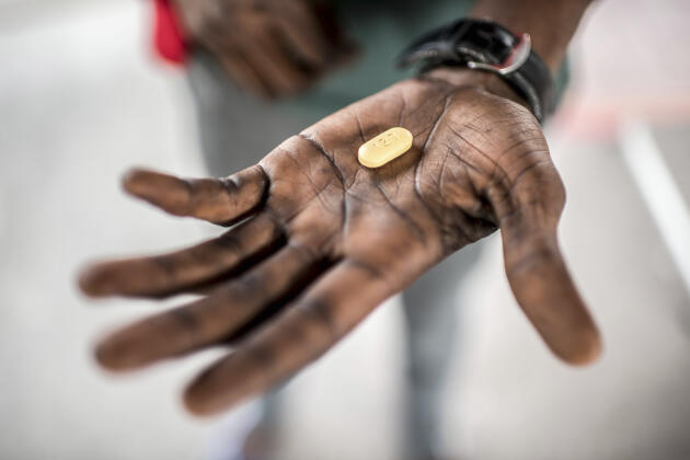 Un homme séropositif tient un comprimé d’antirétroviral à l’hôpital de Kabinda, en République démocratique du Congo.