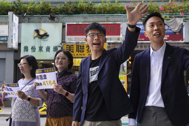 Le candidat Kelvin Lam (droite) et le militant prodémocratie Joshua Wong ont remercié les électeurs devant une station de métro de Hongkong, lundi 25 novembre.