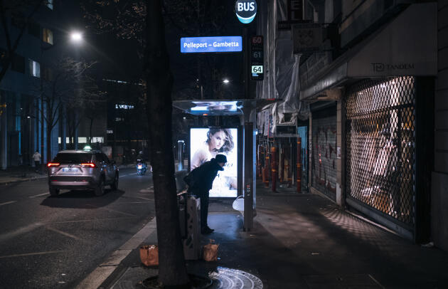 Une personne regarde les horaires modifiés du réseau de bus à la station Pelleport  dans le 20e arrondissement.