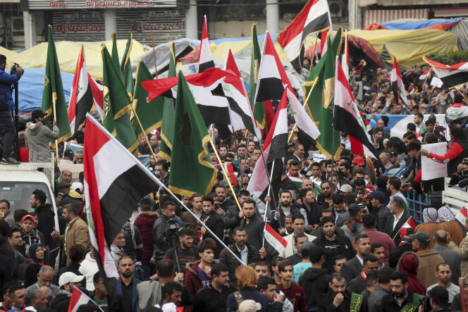 Des manifestants tenant des drapeaux irakiens et des unités de la Mobilisation populaire défilent vers la place Tahrir, à Bagdad, le vendredi 6 décembre.