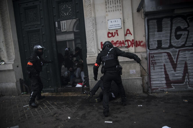 Au niveau du 5 du boulevard de Magenta, à Paris, le jeudi 5 décembre. Le policier de droite, au-dessus de l’homme à terre, porte sur son dos les inscriptions « Police » et « ULI2R », l’identifiant comme un policier de la Préfecture de police de Paris.