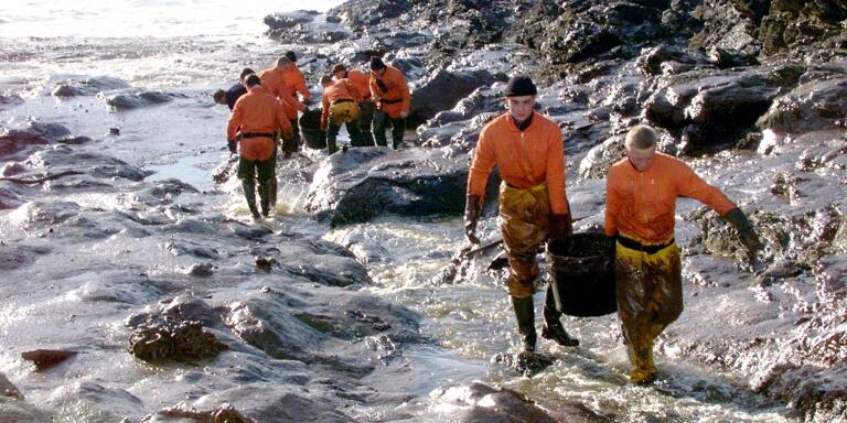 (FILES) In this file photo taken on December 29, 1999, French Civil Security soldiers carry garbage cans filled with oil they recovered on rocks on the western French island of Belle-Ile, following the sinking of the Maltese-registered tanker Erika off the coast of Brittany. The Erika tanker split in half and sank south of Brittany's Finistere department on December 11, 1999, while carrying 30,000 tons of heavy fuel, causing one of the worst oil spills in France, affecting 400 km of coastline from the tip of Brittany to the Ile de Re.  
 / AFP / MARCEL MOCHET
